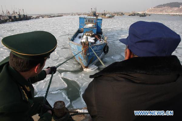 Soldiers help fishermen to tie boats at Zhifu Island in eastern China&apos;s Shandong Province, Jan. 17, 2011. The thickness of the freezing ice has amounted to 15 to 20 centimeters due to continuous cold waves while most offshore activities were forced to be halted. 