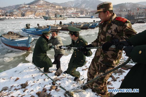 Soldiers help fishermen to tie boats at Zhifu Island in eastern China&apos;s Shandong Province, Jan. 17, 2011. The thickness of the freezing ice has amounted to 15 to 20 centimeters due to continuous cold waves while most offshore activities were forced to be halted. 