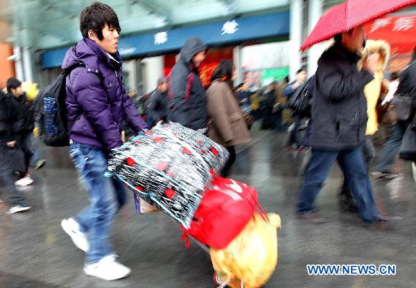 Passengers walk in cold weather on the square outside the railway station in east China's Shanghai, Jan. 18, 2011. China's Spring Festival falls on Feb. 3 this year. This year's holiday travel peak will be from Jan. 19 to Feb. 27. 
