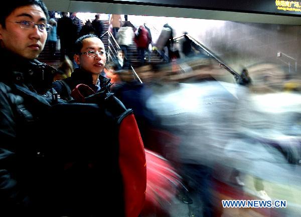 Zhou Liqiang (2nd L), a university student from Taiyuan City, waits for the train with his schoolmate outside the railway station of east China's Shanghai, Jan. 18, 2011. 
