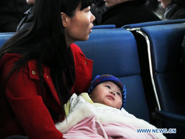 A mother holds her baby in arms at the waiting hall of Changchun Railway Station in Changchun, capital of northeast China's Jilin Province, Jan. 18, 2011. 
