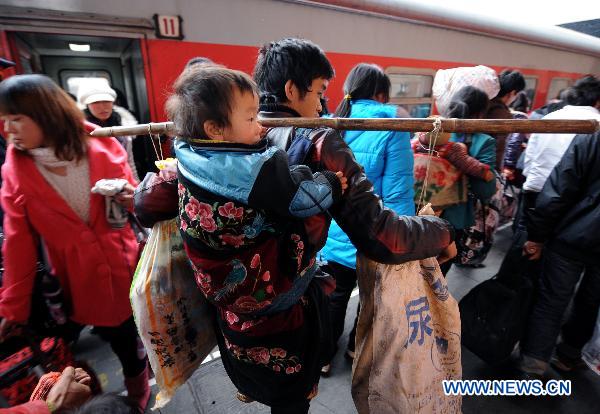 A migrant worker carrying his child on his back boards on a train at the railway station in Hangzhou, capital of east China's Zhejiang Province, Jan. 18, 2011. 