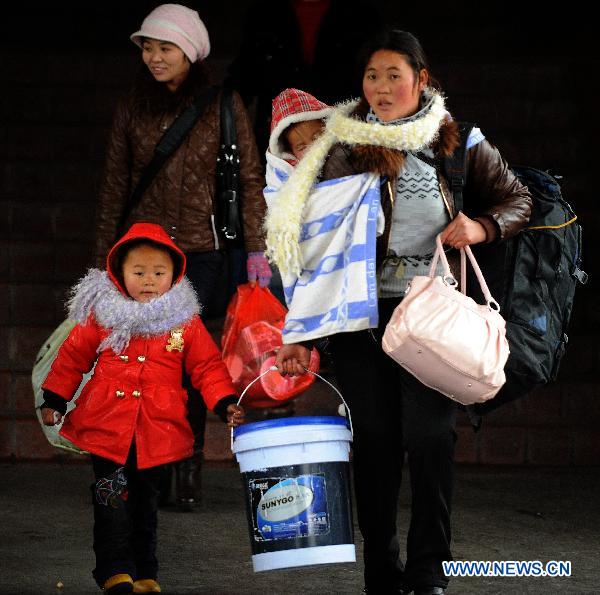 A woman taking her children walks to board on a train bounding for southwest China's Chengdu, at the railway station in Hangzhou, capital of east China's Zhejiang Province, Jan. 18, 2011.