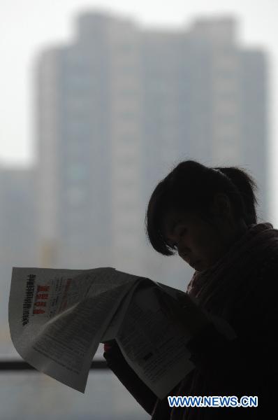 A job seeker reads position information in Hangzhou, capital of east China&apos;s Zhejiang Province on Jan. 18, 2011. 
