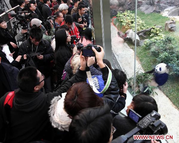 People take photos of panda &apos;Xin Xin&apos; at the newly-launched panda pavilion in the Macao Special Administrative Region, south China, Jan. 18, 2011.