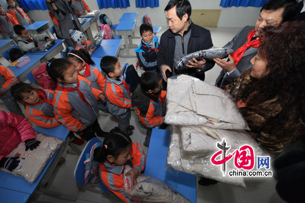 Children of migrant workers receive cotton-padded jackets for New Year at a primary school in Chongqing on Sunday. [China.com.cn]