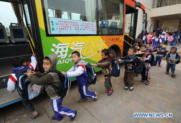 Pupils get on a school bus in the new primary school at the relocation area in Longlou Township of Wenchang, south China's Hainan Province, Jan. 11, 2011. 