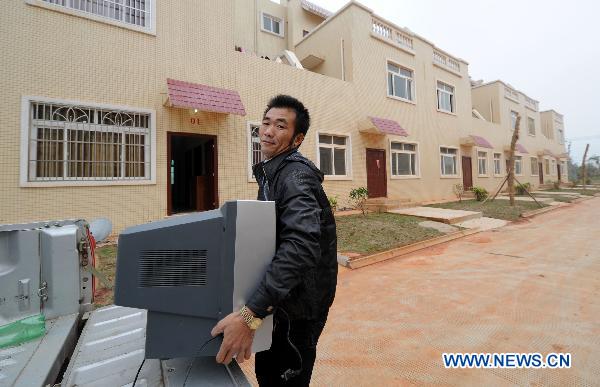Villager Zheng Yin (R), moves belongings into the new house in relocation area in Longlou Township of Wenchang, south China's Hainan Province, Jan. 11, 2011.