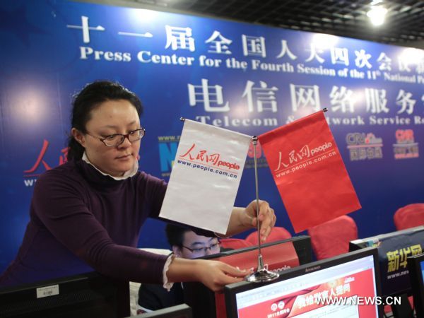 A staff member of People.com.cn, a leading news portal, places a desk banner with her company's logo at the media center for 'Lianghui', namely the two annual sessions of the National People's Congress (NPC) and the National Committee of Chinese People's Political Consultative Conference (CPPCC), in Beijing, capital of China, Feb. 26, 2011. 
