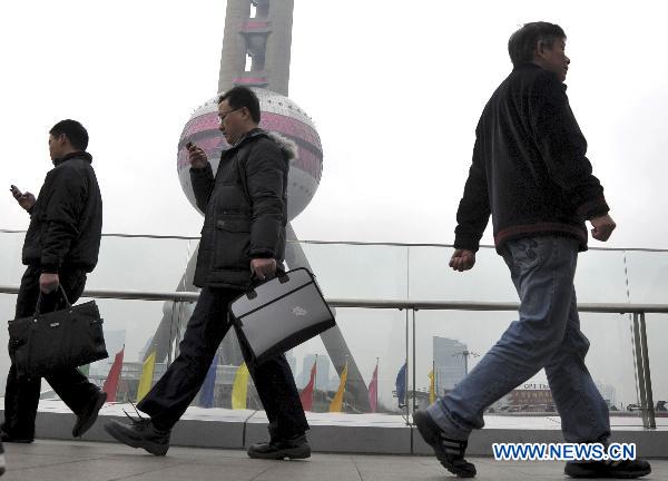 Pedestrians pass through the Oriental Pearl TV Tower in Shanghai, east China, March 14, 2011.