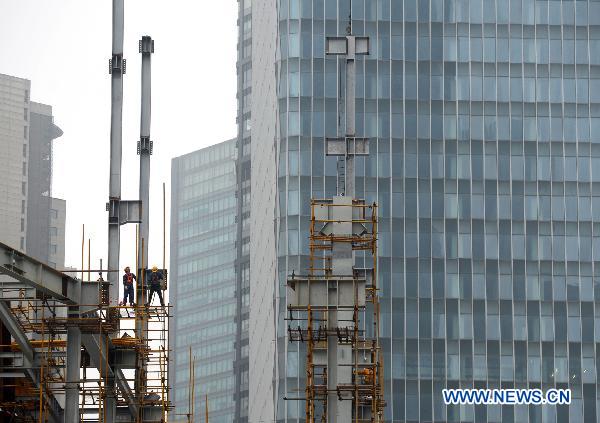 Workers go on with construction of a large building as usual in Shanghai, east China, March 14, 2011. 