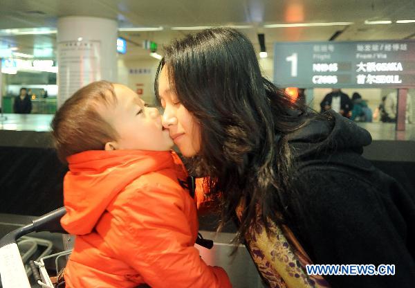 A baby evacuated from quake-hit Japan kisses his mother after arriving at the Dalian Zhoushuizi International Airport in Dalian, northeast China's Liaoning Province, March 16, 2011.
