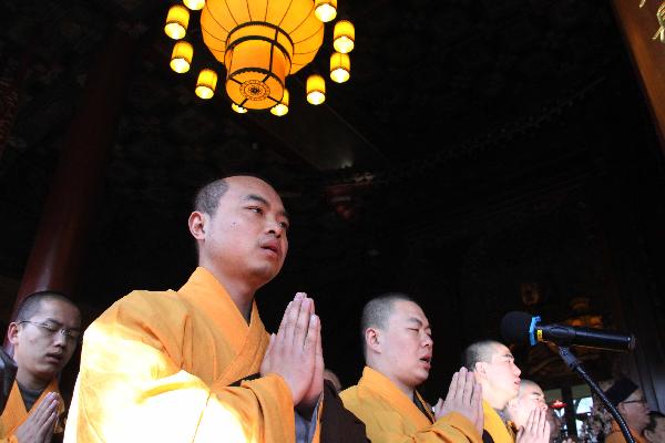 Members of Buddhist Association of China pray for the lost lives during the earthquake that took place in Japan last week in Beijing, capital of China, March 16, 2011.