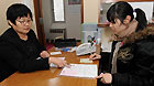 A staff of Chinese Consulate General in Sapporo helps Wu Di (R), a Chinese student in Japan's Iwate University, with the returning permits in Sapporo, Japan, March 18, 2011.
