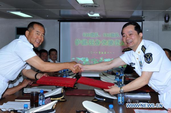 Zhang Huachen (L), commander of the seventh escort flotilla sent by the Chinese Navy to the Gulf of Aden, exchanges documents of escorting mission with Han Xiaohu, commander of the eighth escort flotilla, on the comprehensive supply ship 'Qiandaohu' in the Gulf of Aden, March 18, 2011.