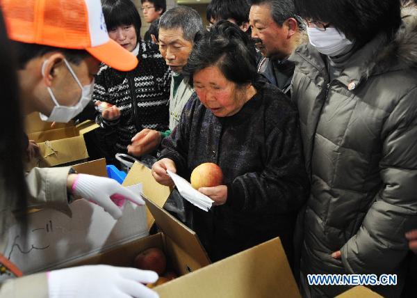 Japanese line for apples inside a sports park used as a makeshift shelter in Fukushima, Japan, March 19, 2011.