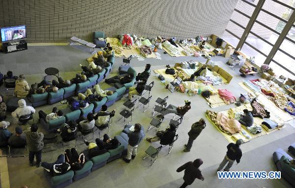 Japanese watch news on TV inside a sports park used as a makeshift shelter in Fukushima, Japan, March 19, 2011. 