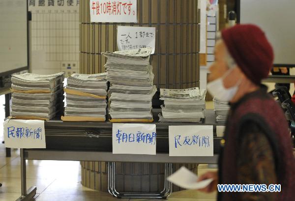 A Japanese walks by newspapers provided by government inside a sports park used as a makeshift shelter in Fukushima, Japan, March 19, 2011. 