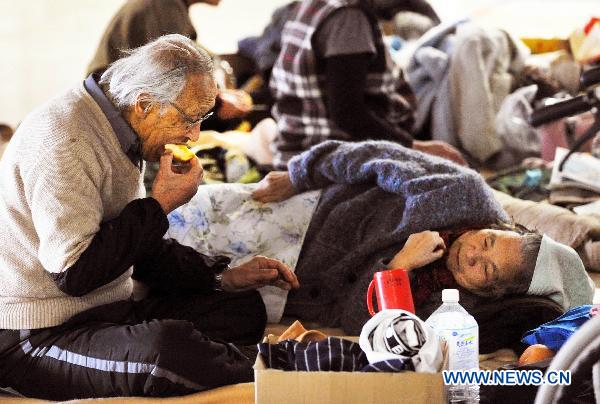 A Japanese eats an apple inside a sports park used as a makeshift shelter in Fukushima, Japan, March 19, 2011. 