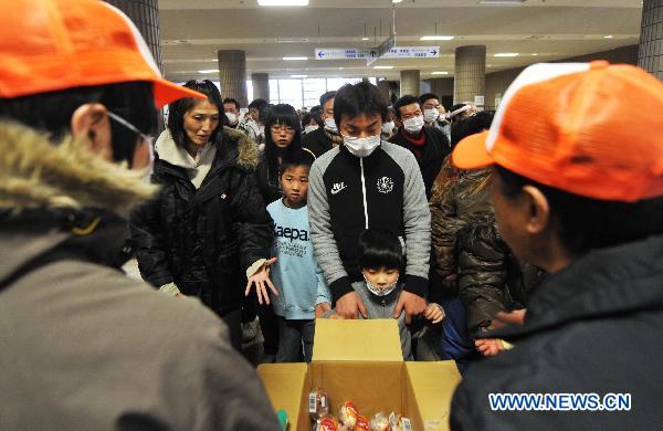 Japanese wait in line for fruit inside a sports park used as a makeshift shelter in Fukushima, Japan, March 19, 2011. 