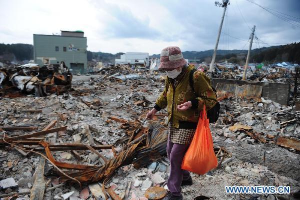 A woman lingers on the site where her home was located among debris in quake-devastated Iwate Prefecture, Japan, on March 22, 2011. 