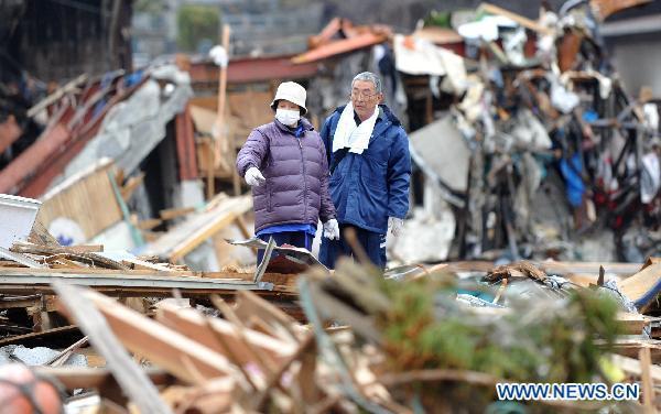 A couple stands on the site where their home was located among debris in quake-devastated Iwate Prefecture, Japan, on March 21, 2011. 