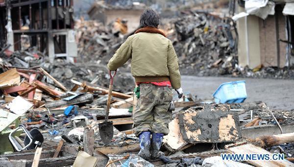 A man rests on the site where his home was located among debris in quake-devastated Iwate Prefecture, Japan, on March 21, 2011. 