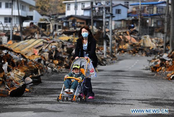 A woman trolleys her child among debris in quake-devastated Iwate Prefecture, Japan, on March 22, 2011. 