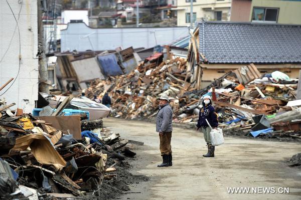 Two people walk among building debris in Kesennuma, Miyagi-ken in Japan, March 21, 2011.
