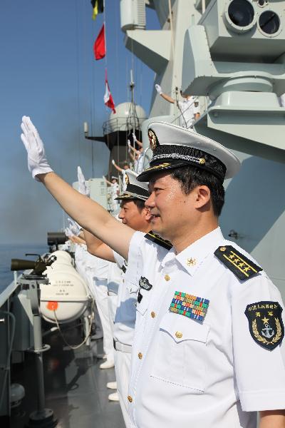 Officers and soldiers of Chinese Navy's eighth batch of escort flotilla wave to the seventh batch of escort flotilla during a ceremony for farewell navigation in Gulf of Aden, March 22, 2011. 