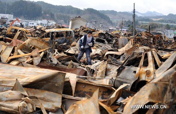 A local resident searches for belongings among ruined houses in the quake-hit Oshikacho of Miyagi Prefecture, Japan, March 23, 2011.