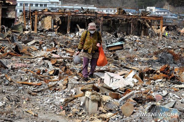 A local resident searches for belongings among ruined houses in the quake-hit Oshikacho of Miyagi Prefecture, Japan, March 23, 2011.