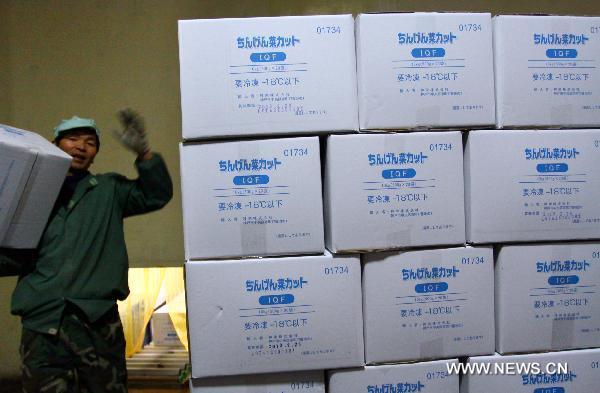A labour carries a package of frozen vegetables at a food factory in Jiashan of east China&apos;s Zhejiang Province, March 24, 2011.