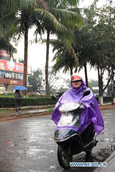A citizen rides on a street on a rainy day in Haikou, capital of south China's Hainan Province, March 29, 2011. 