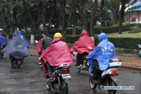 Citizens ride on a street on a rainy day in Haikou, capital of south China's Hainan Province, March 29, 2011. 