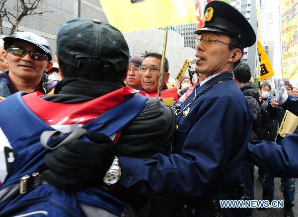 Protesters confront with policemen in front of the head office of Tokyo Electric Power Company, Inc. (TEPCO) during an anti-nuclear march in Tokyo, Japan, March 31, 2011.