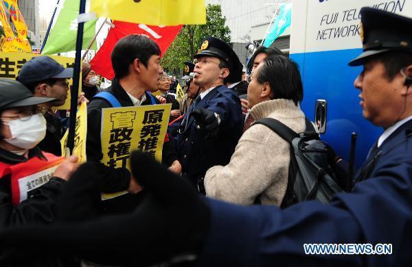 Protesters confront with policemen in front of the head office of Tokyo Electric Power Company, Inc. (TEPCO) during an anti-nuclear march in Tokyo, Japan, March 31, 2011.