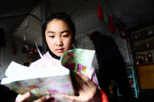 Metok Lhaze reads in a government-furnished tent in Jiegu town of Yushu county, April 11, 2011. The fifth-grader loves to dance and wants to become an architect and designer, so she can build fine houses in her hometown. 