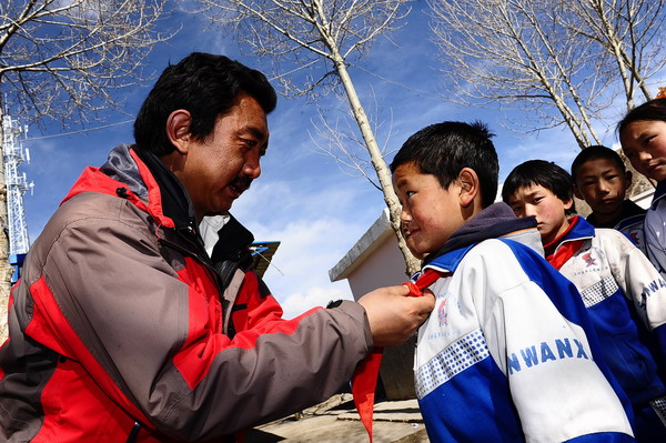 Nyima Gyatsoi, a primary school principal in Yushu, ties red scarves for his pupils on April 9, 2011. The principal is looking after 2,000 students, among whom more than 100 were orphaned by the massive quake one year ago. He hopes some kindhearted people can help the students.