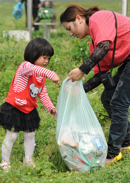 A woman and her child collect trash at Dongjing River Dike in Qianjiang City, central China's Hubei Province, April 18, 2011. 