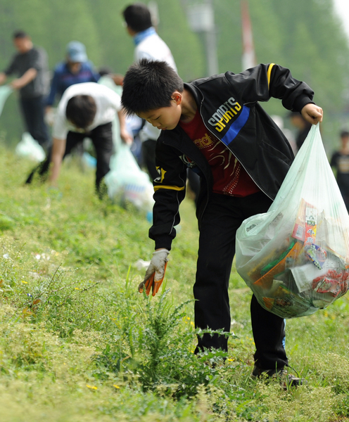 People pick up trash at Dongjing River Dike in Qianjiang City, central China's Hubei Province, April 18, 2011. 