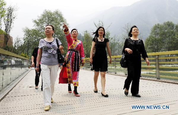 A guide (3rd R) wearing the traditional dress of Qiang ethnic group introduces the post-quake reconstruct to visitors in the rebuilt Yingxiu Town of southwest China's Sichuan Province on April 30, 2011. 