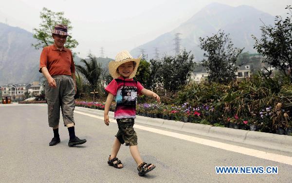 A senior citizen takes a walk with his grandson in a tourist avenue in the rebuilt Yingxiu Town of southwest China's Sichuan Province on April 30, 2011.