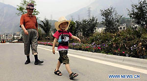 A senior citizen takes a walk with his grandson in a tourist avenue in the rebuilt Yingxiu Town of southwest China's Sichuan Province on April 30, 2011.
