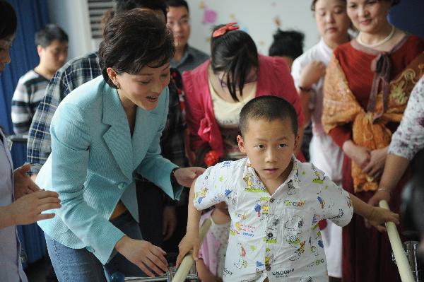 A child(R) injured from Wenchuan earthquake tries to walk with the aid of rehabilitation equipment under the encouragement of Yang Lan (L), the Chinese goodwill ambassador of the United Nations Children&apos;s Fund (UNICEF) at Mianzhu Traditional Chinese Medicine Hospital in Mianzhu, southwest China&apos;s Sichuan Province, May 6, 2011.