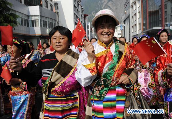 People in traditional costumes wave China's national flag in Lixian County, southwest China's Sichuan Province, May 8, 2011. Some 5,000 local residents gathered and paraded to celebrate the rebirth of their hometown after the devastating earthquake flattened the county on May 12, 2008. Reconstruction has cost over 2 billion Yuan so far. 