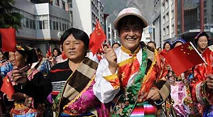 People in traditional costumes wave China's national flag in Lixian County, southwest China's Sichuan Province, May 8, 2011. Some 5,000 local residents gathered and paraded to celebrate the rebirth of their hometown after the devastating earthquake flattened the county on May 12, 2008. Reconstruction has cost over 2 billion Yuan so far.