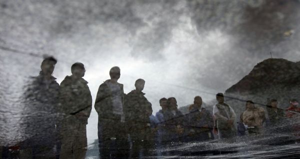 Photo taken on May 9, 2011 shows the water reflection of volunteers standing in silent tribute to lost lives in the earthquake three years ago in Qingchuan, southwest China&apos;s Sichuan Province. 