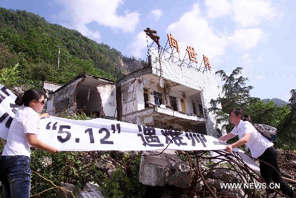 Two teachers hang up a banner to mourn those teachers and students killed in the massive earthquake three years ago at the original site of Qushan Primary School in Beichuan County, southwest China's Sichuan Province, May 10, 2011. 