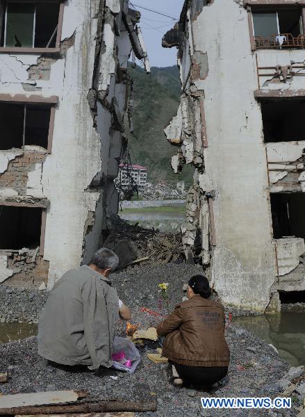 People burn joss paper to commemorate their beloved families lost in the 2008 Wenchuan earthquake in front of a destroyed building in Beichuan, southwest China's Sichuan Province, May 12, 2011. 